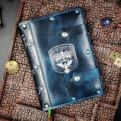 Handmade A5 leather adventure journal featuring a hand-gilded Ravenclaw eagle crest, Marauder's Map footprints, and a wand duel spine design by Grimbeard Leather