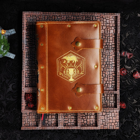 Handmade A5 leather adventure journal featuring a hand-gilded Hufflepuff badger crest, Marauder's Map footprints, and a wand duel spine design by Grimbeard Leather