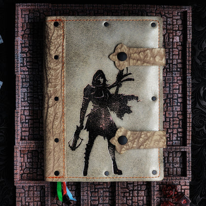 Handmade A5 leather adventure journal with hand-gilded hooded female rogue with crossbow design by Grimbeard Leather