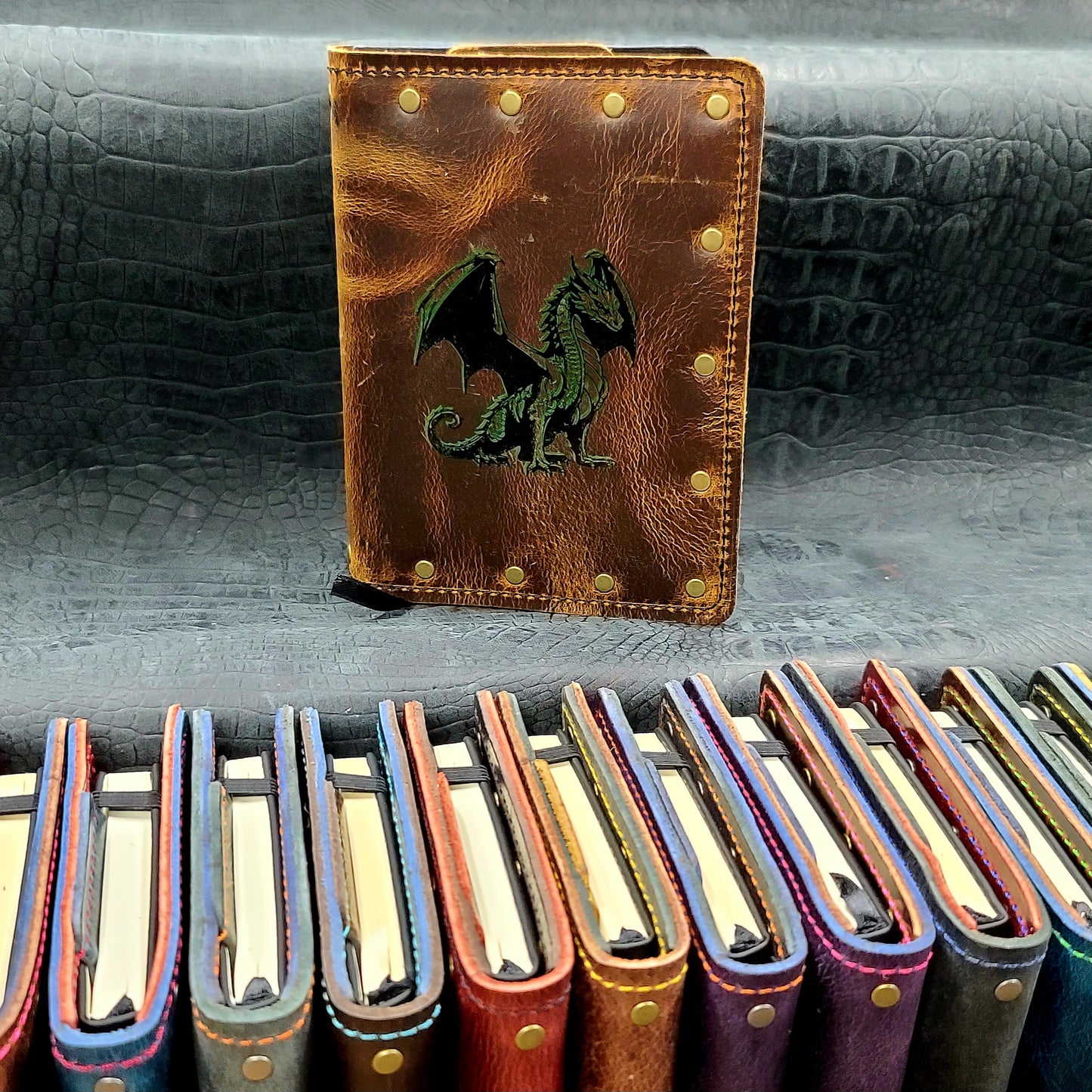 Custom handmade leather pocket journal with hand-gilded seated dragon and open wings design by Grimbeard Leather