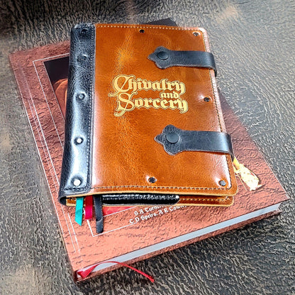 Officially licensed Chivalry and Sorcery RPG leather A5 journal featuring the logo of Brittannia Game Designs Ltd, handcrafted by Grimbeard Leather